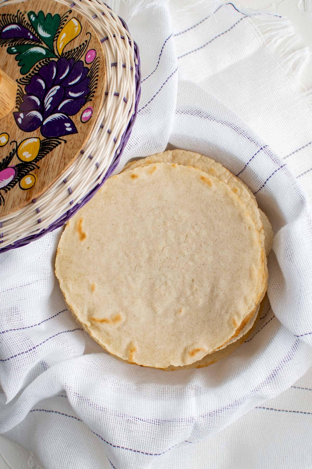 homemade corn tortillas in a basket with a white towel