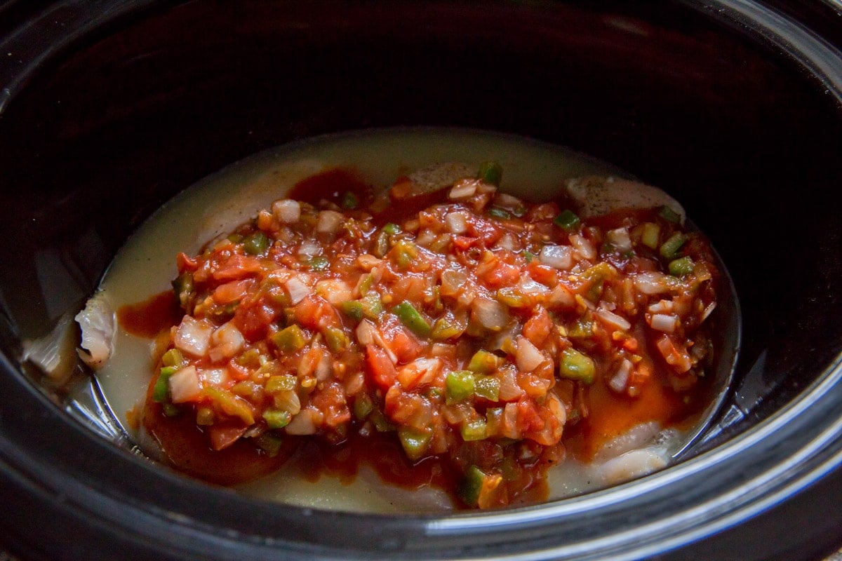 salsa poured over chicken breasts in slow cooker