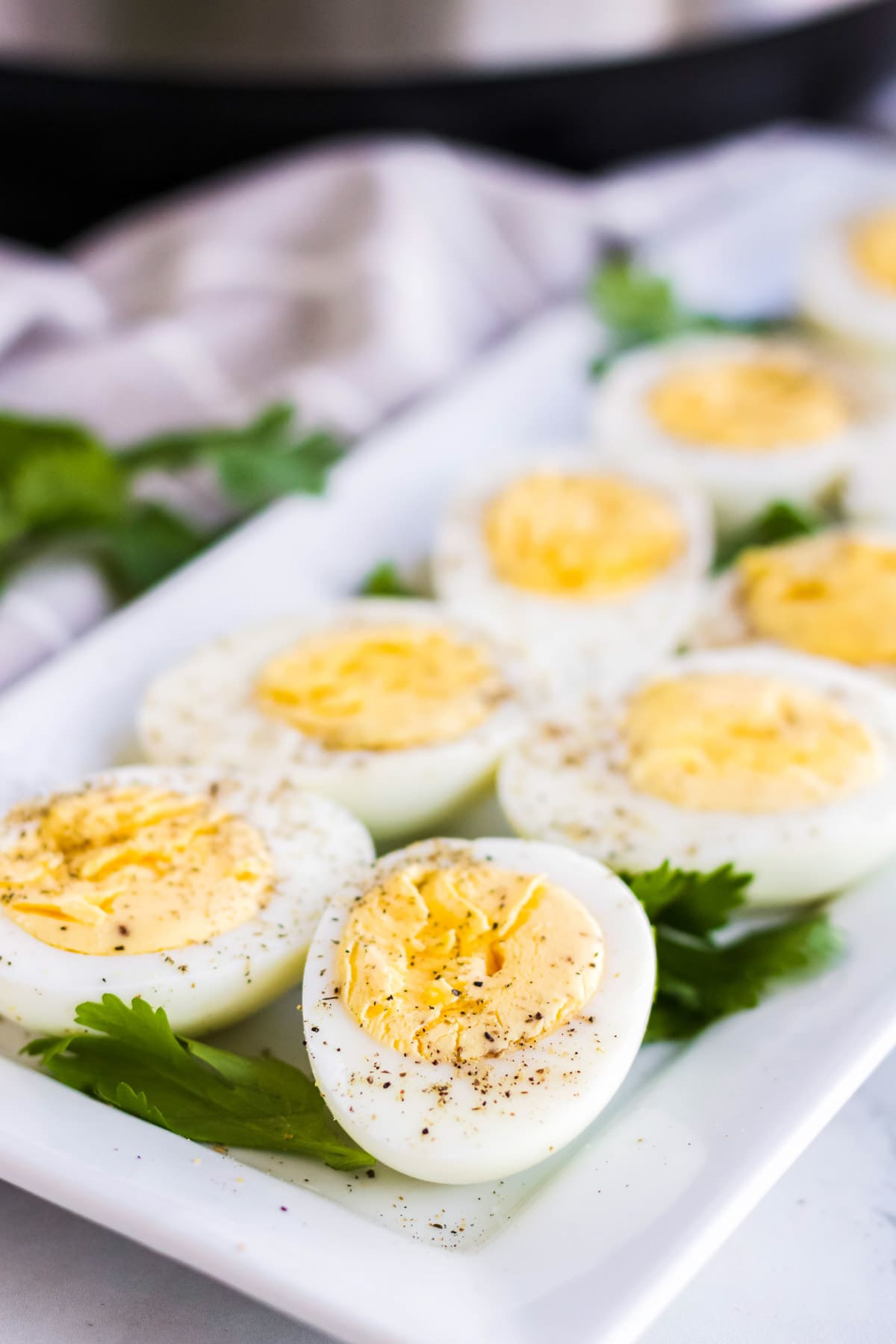 hard boiled eggs, sliced in half, instant pot, white platter, white towel, pepper