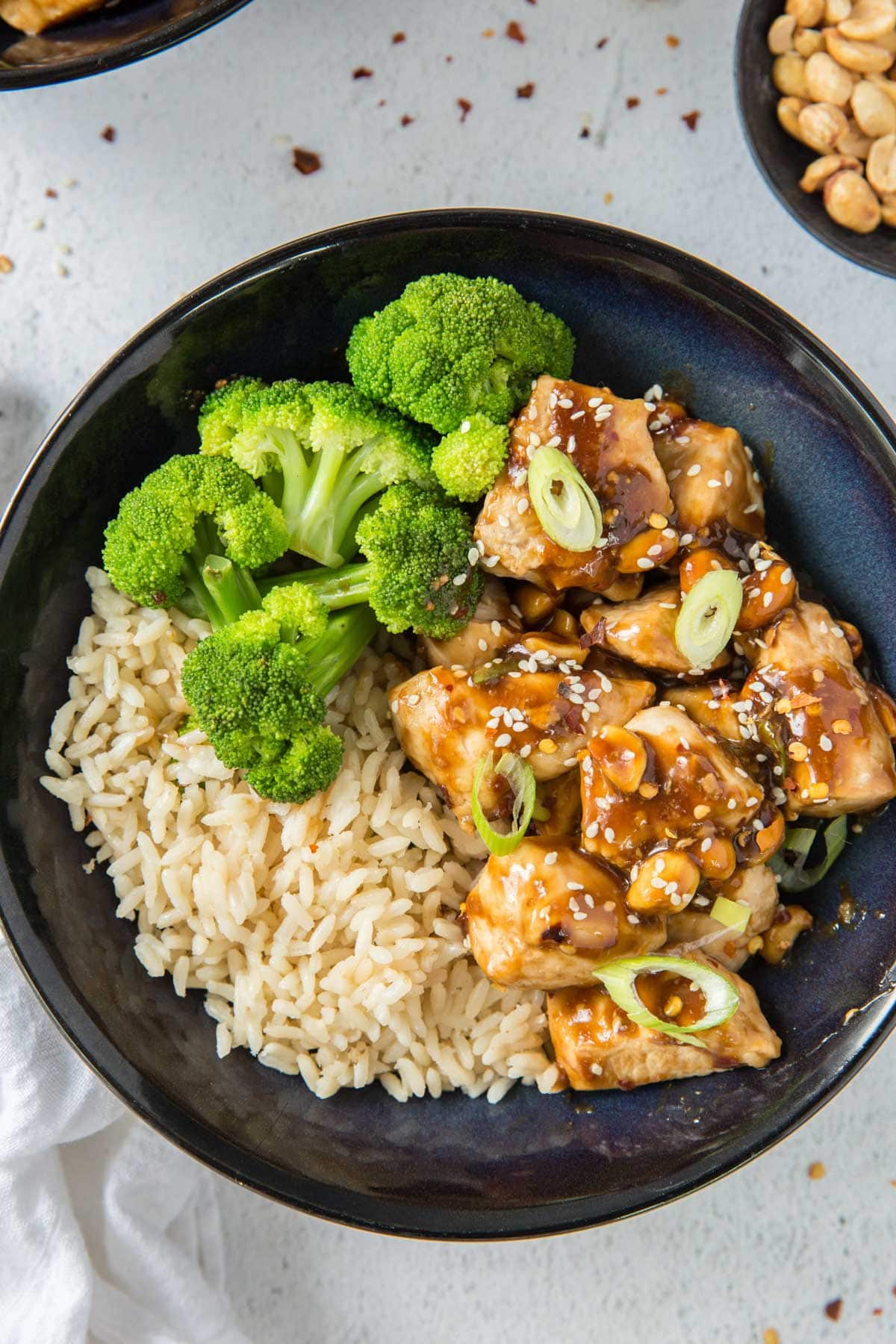 bowl of rice, kung pao chicken, broccoli, red pepper flakes, sesame seeds