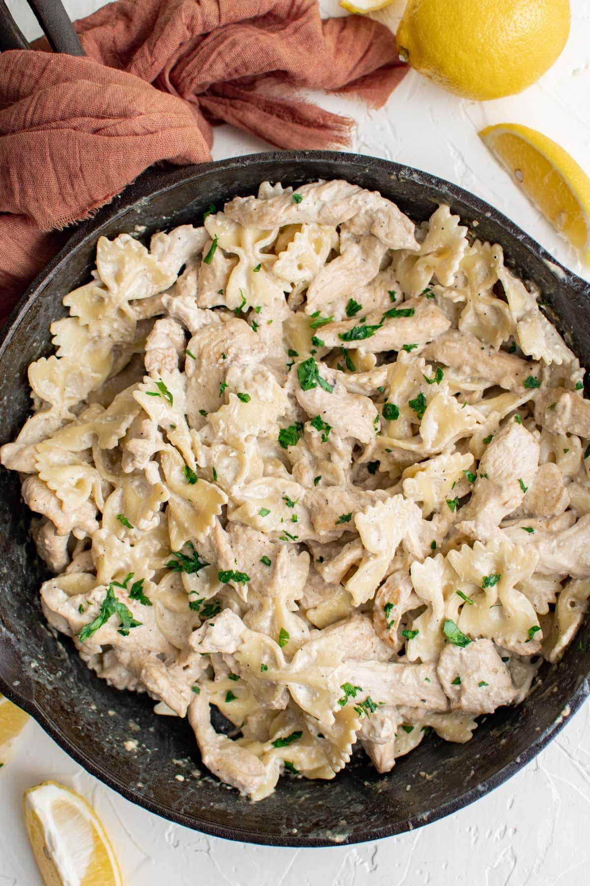 cast iron skillet, lemon chicken pasta, lemon slices, pink napkin