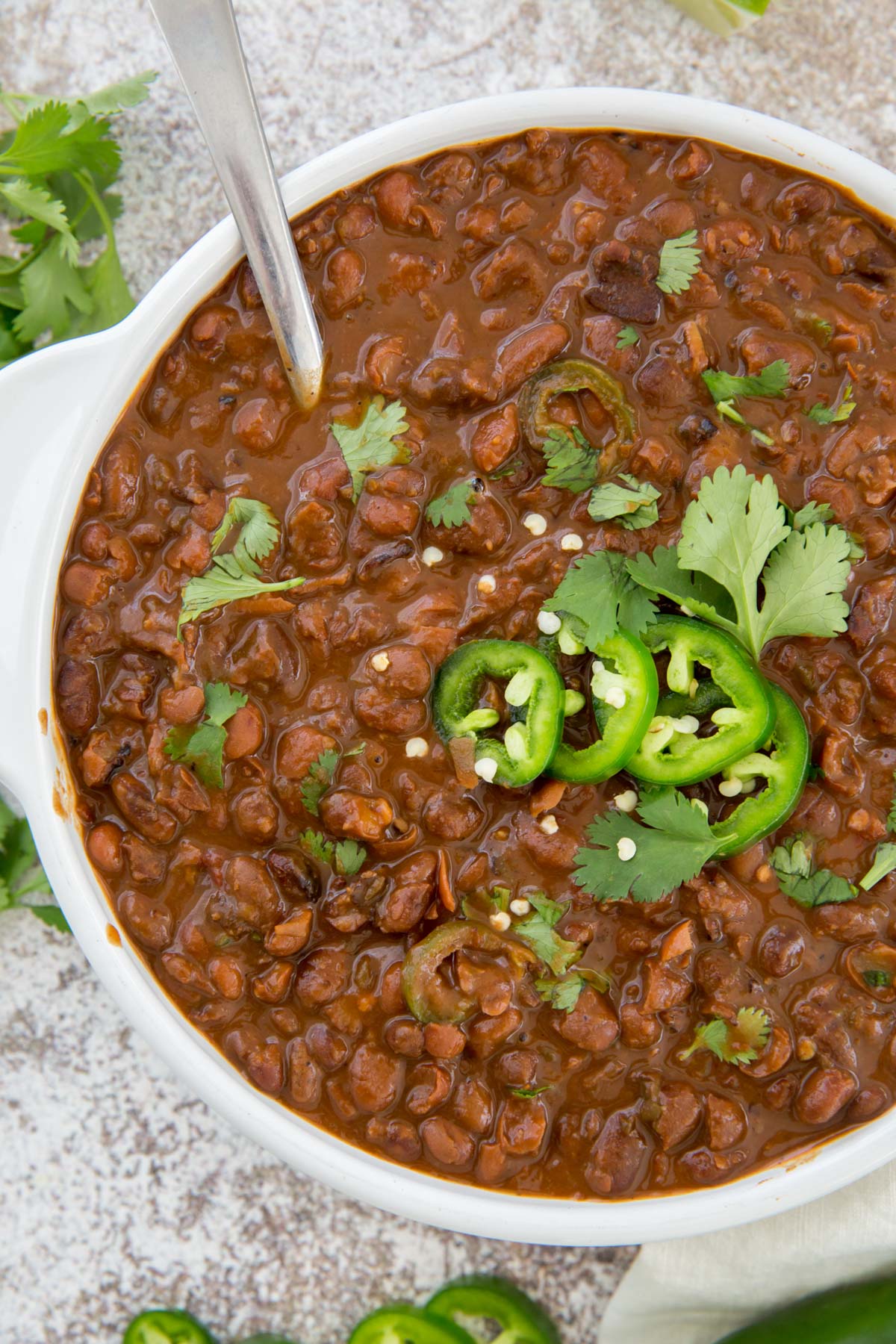 white bowl, pinto beans, jalapeno, cilantro, silver spoon