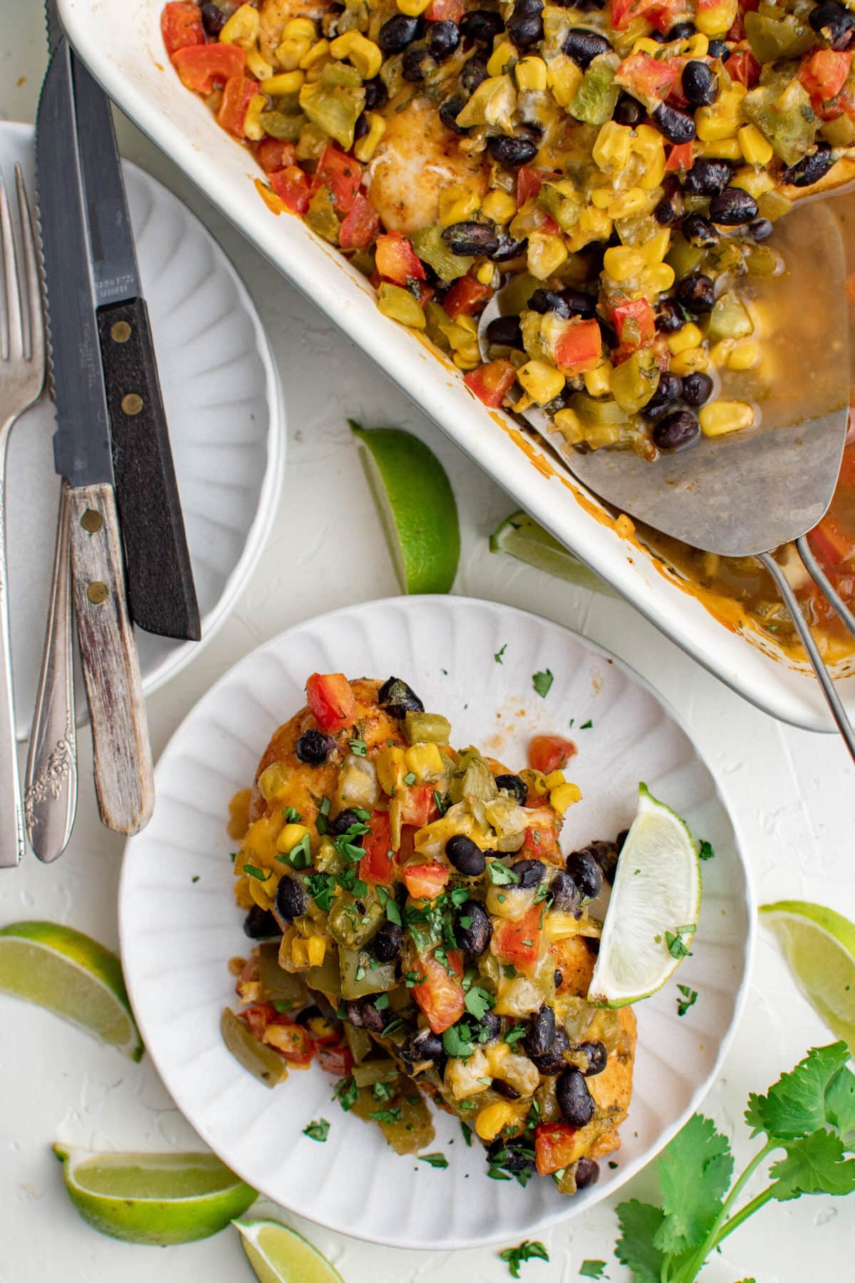 chicken and southwest veggies on a plate, white casserole dish, forks, knives, limes