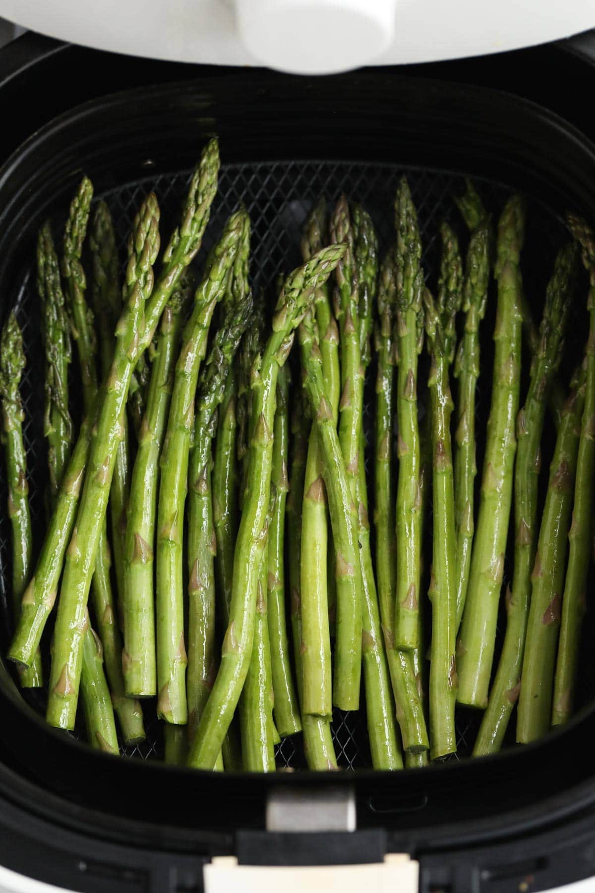 raw asparagus in air fryer basket