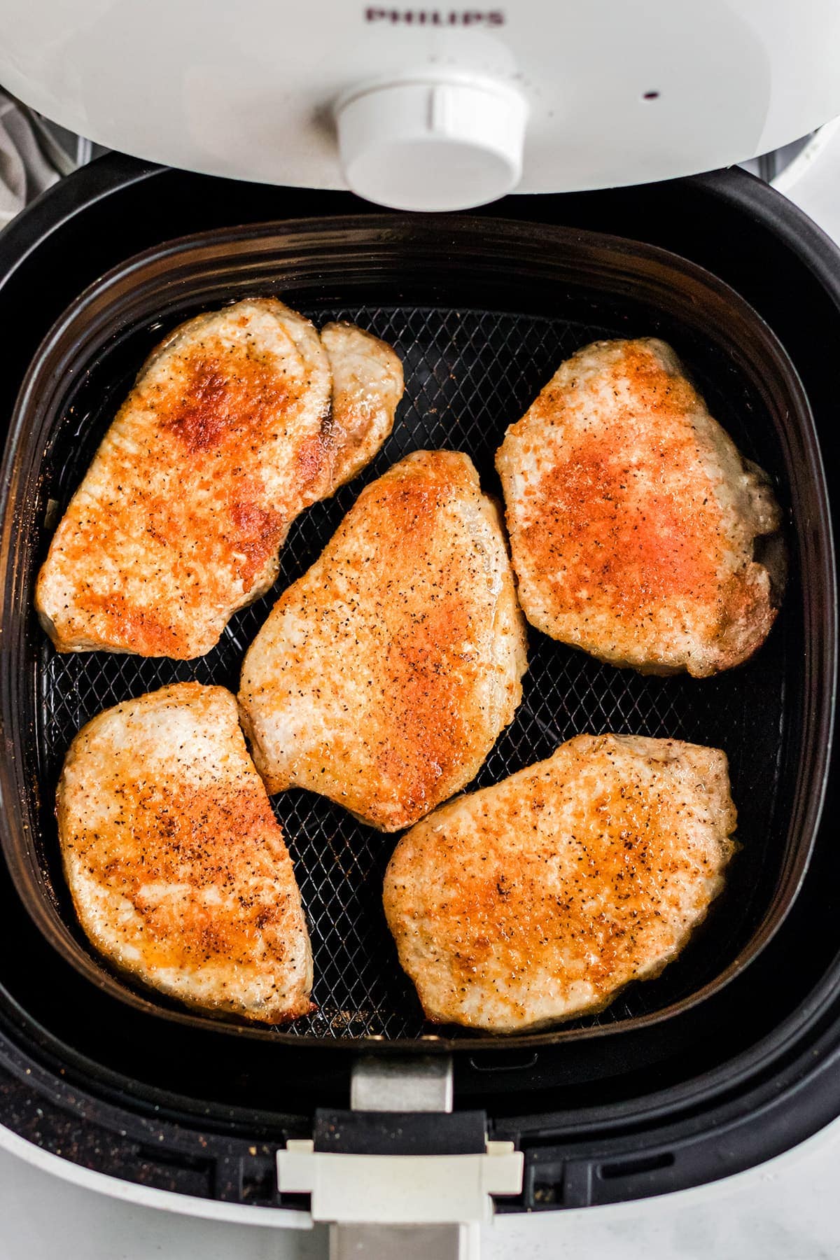 air fryer with pork chops in the basket