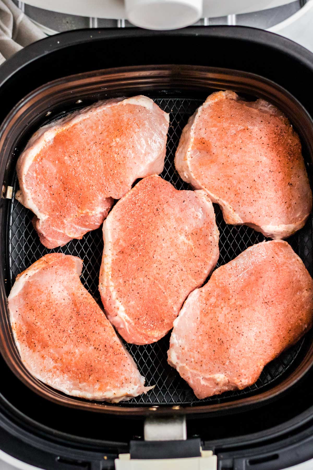 raw pork chops in an air fryer basket