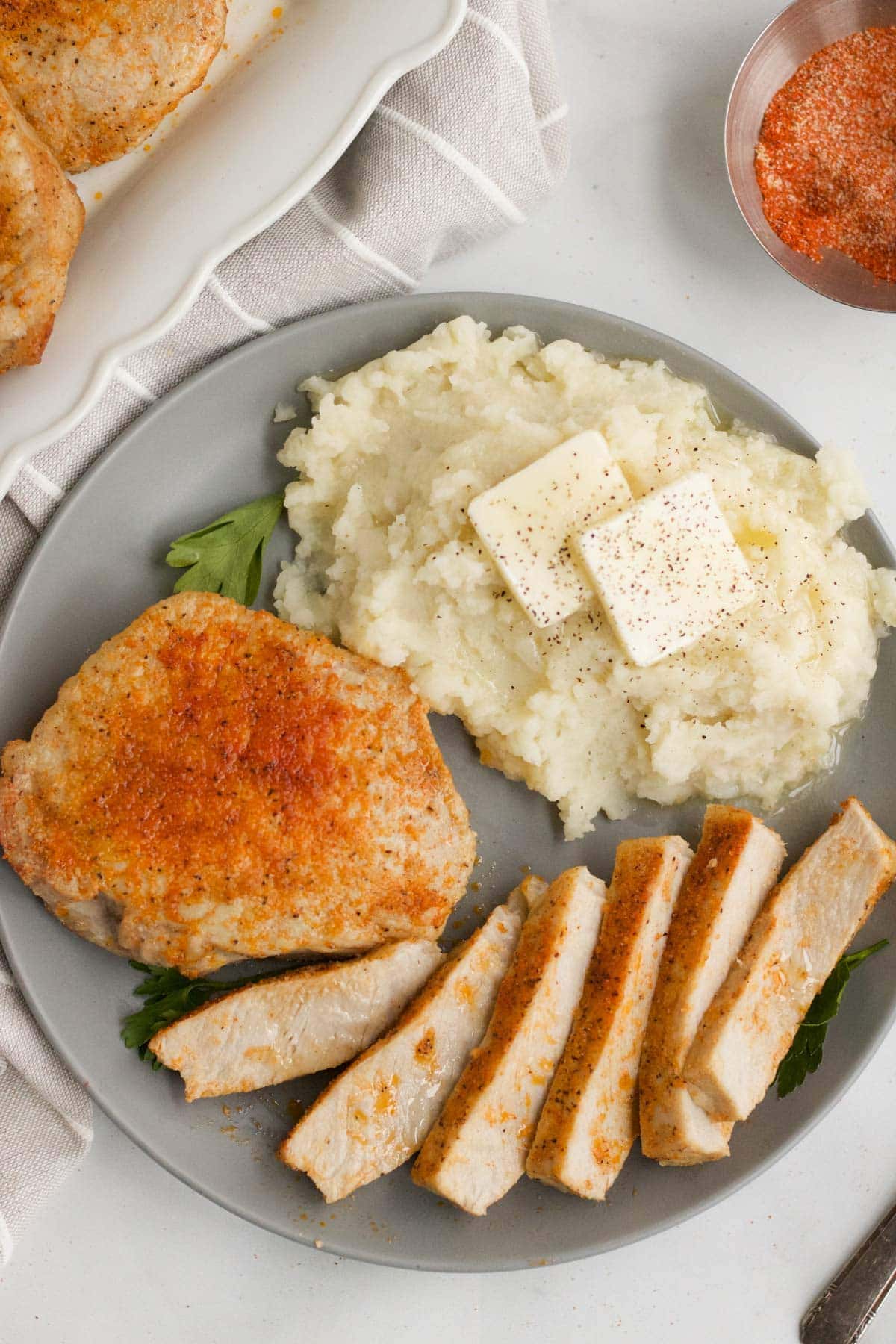overhead picture of plate with mashed potatoes, butter, pork chops, sliced
