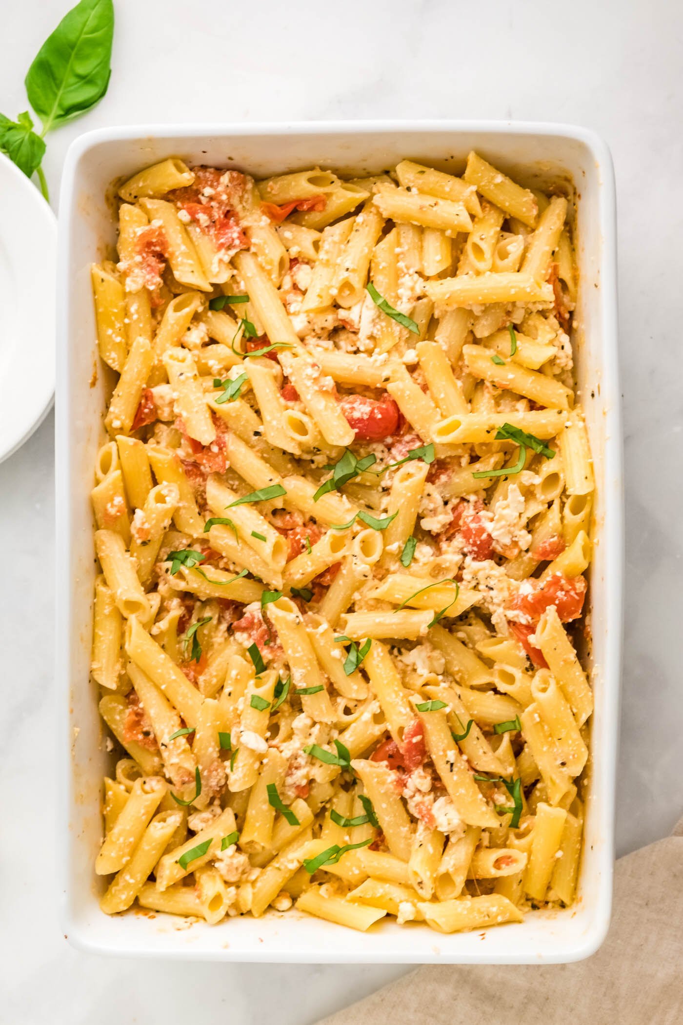 white baking dish, pasta, tomatoes, feta, basil