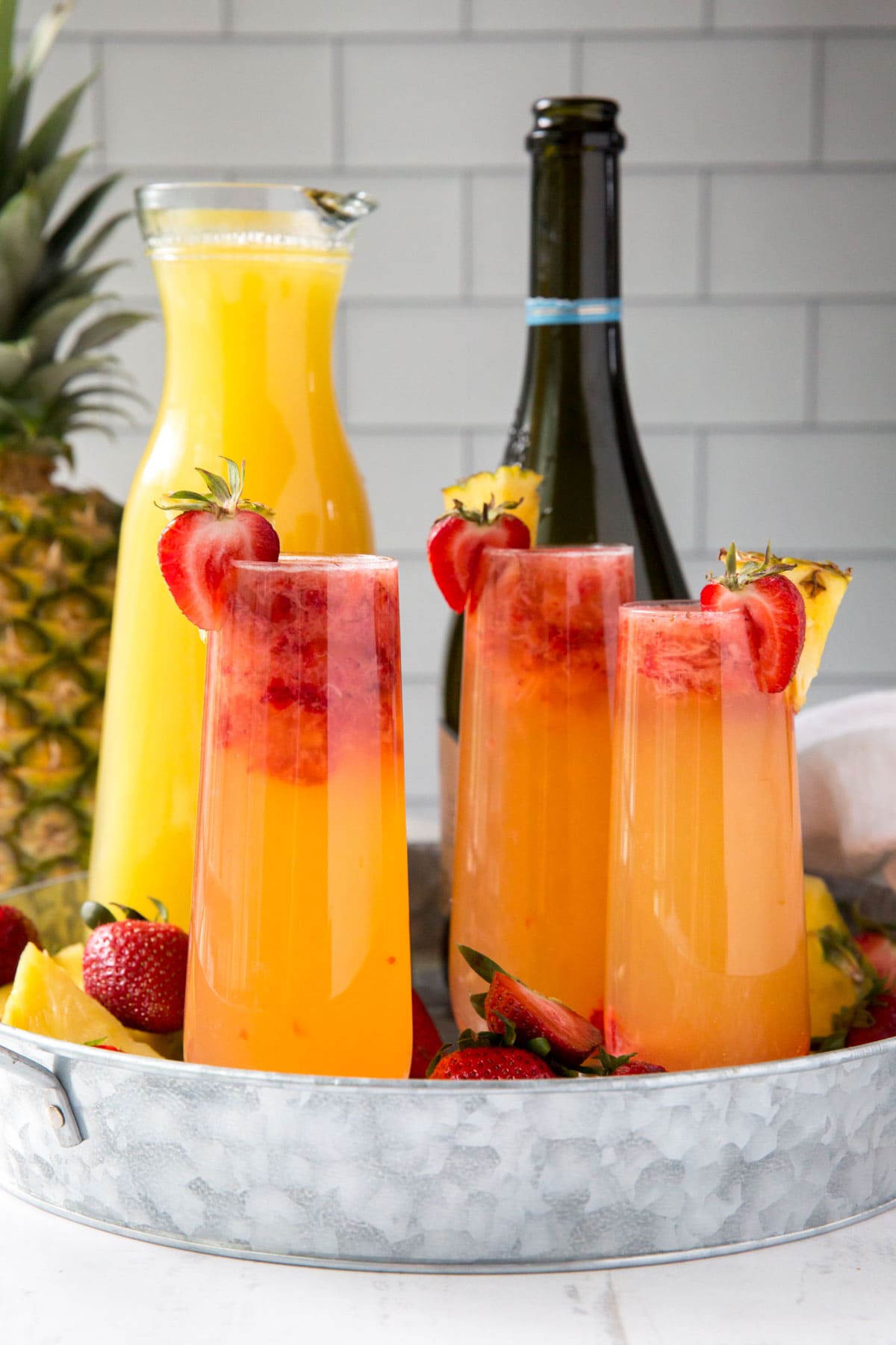 galvanized tray, champagne flutes with pineapple strawberry mimosas, champagne