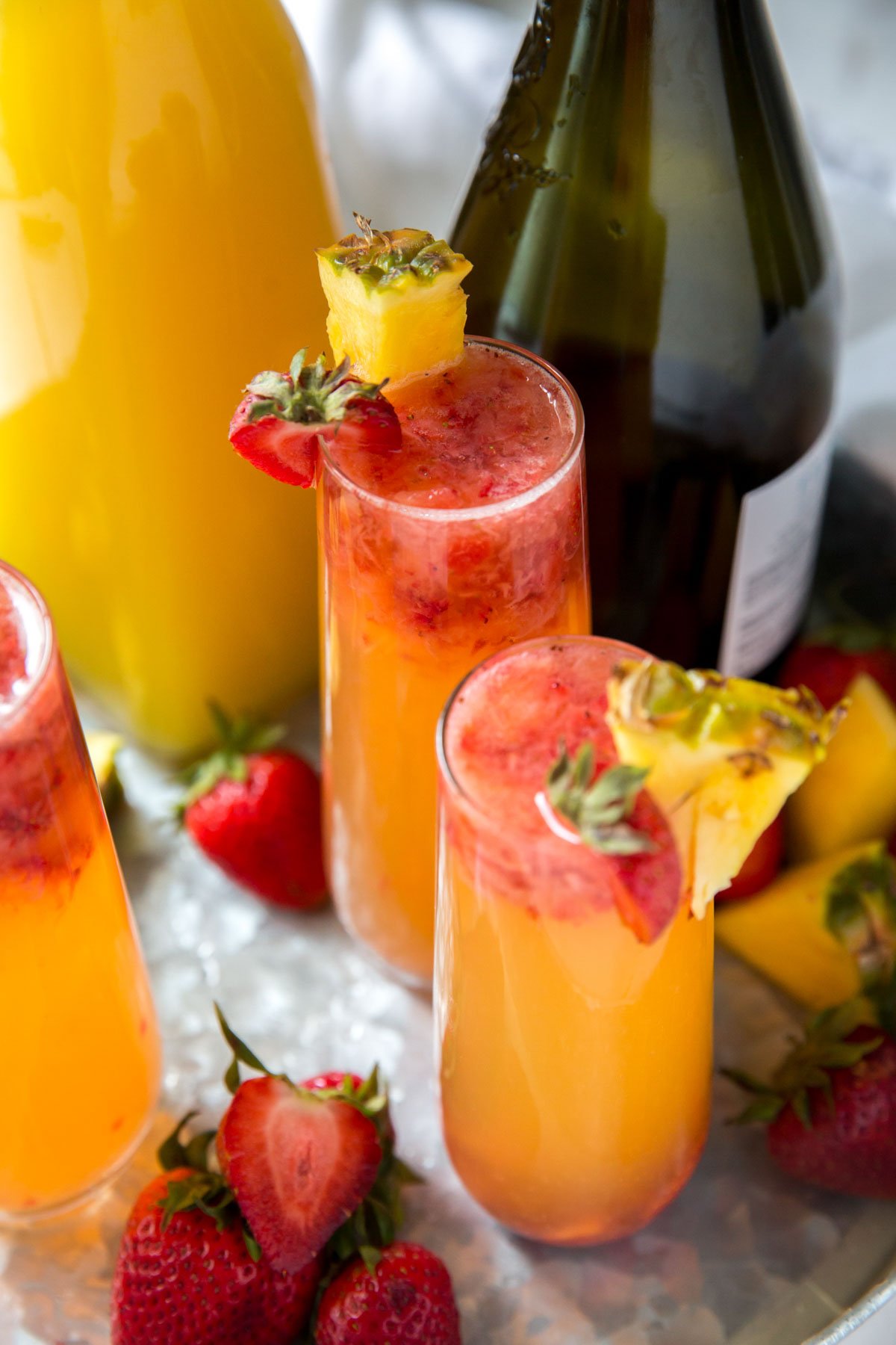 champagne glasses with pineapple juice and strawberries, bottle of champagne