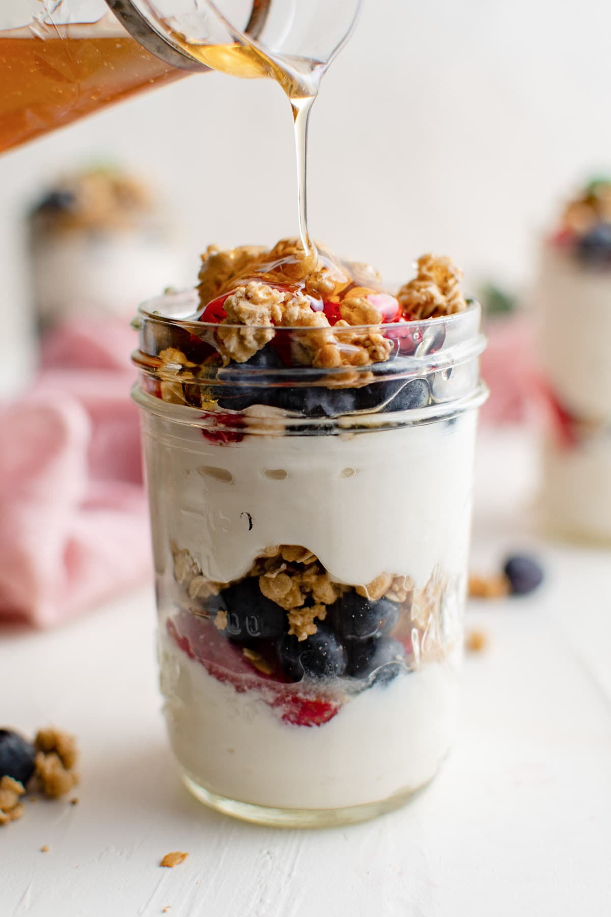 glass jar with yogurt parfait, honey drizzle