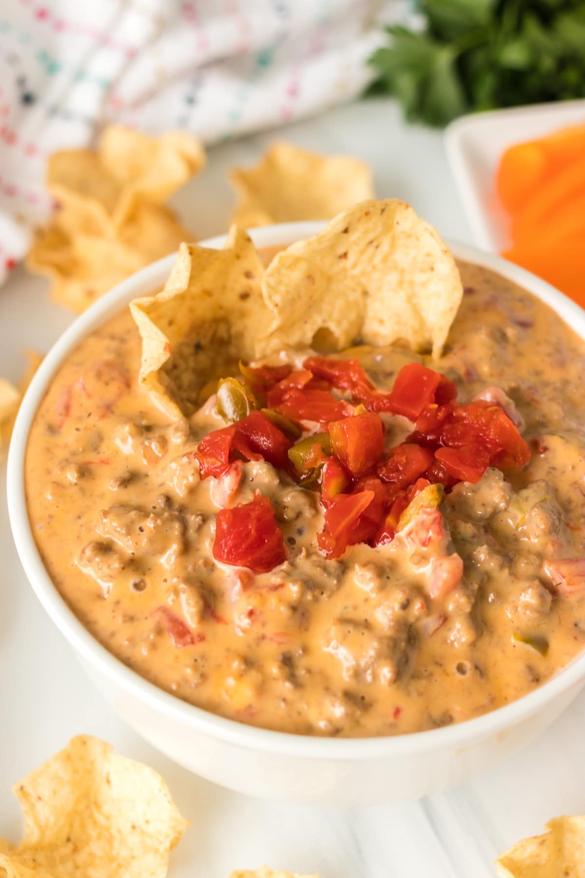 tortilla chips dipped into a white bowl of rotel dip