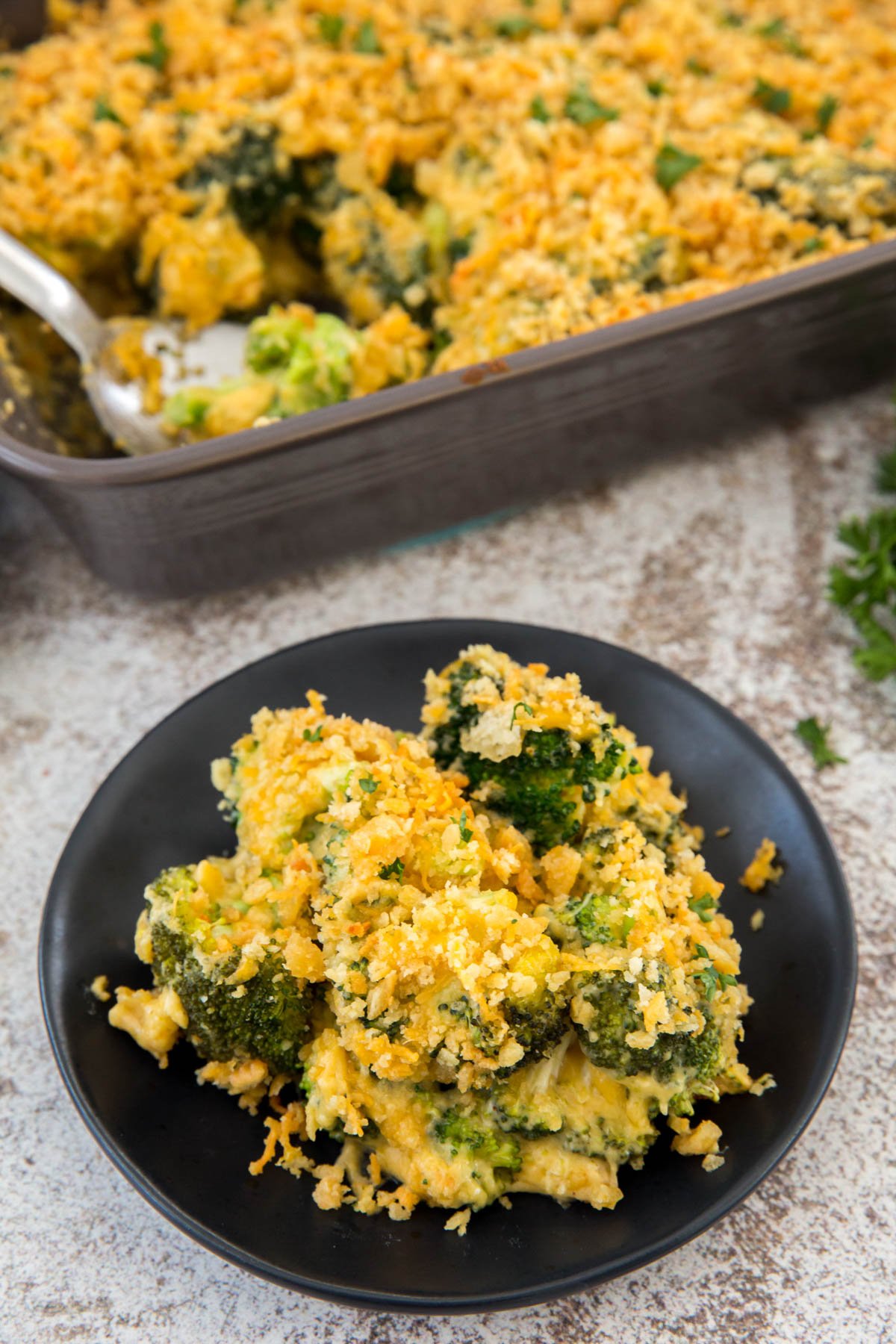 broccoli cheese casserole, black plate, gray baking dish