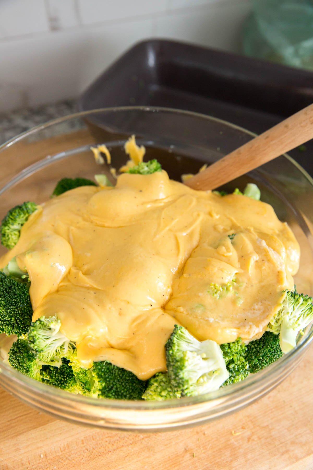 brocolli and cheese sauce, clear glass bowl, wooden spoon