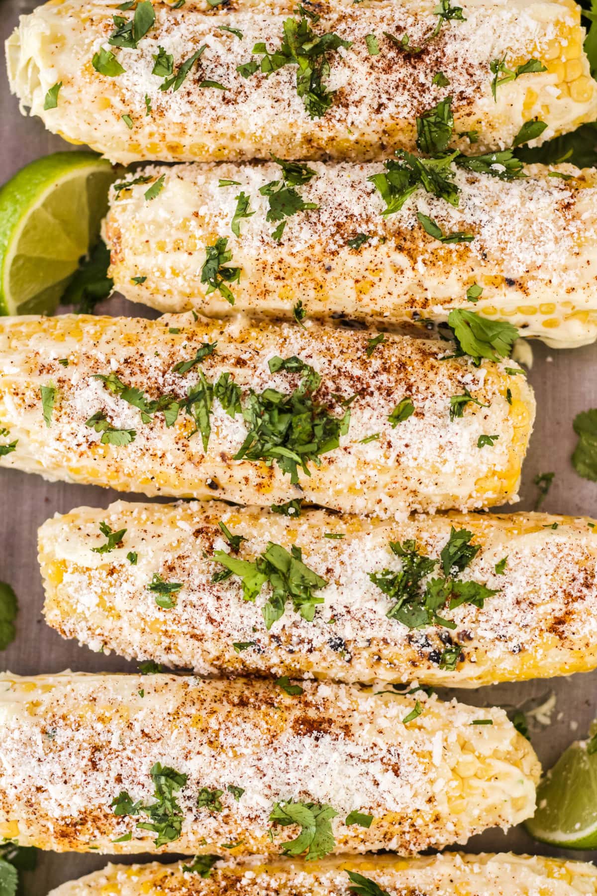 mexican street corn with cilantro and limes on a wood tray