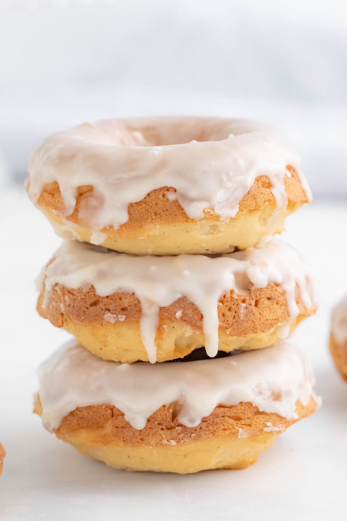 stack of three baked donuts with white glaze dripping down the sides