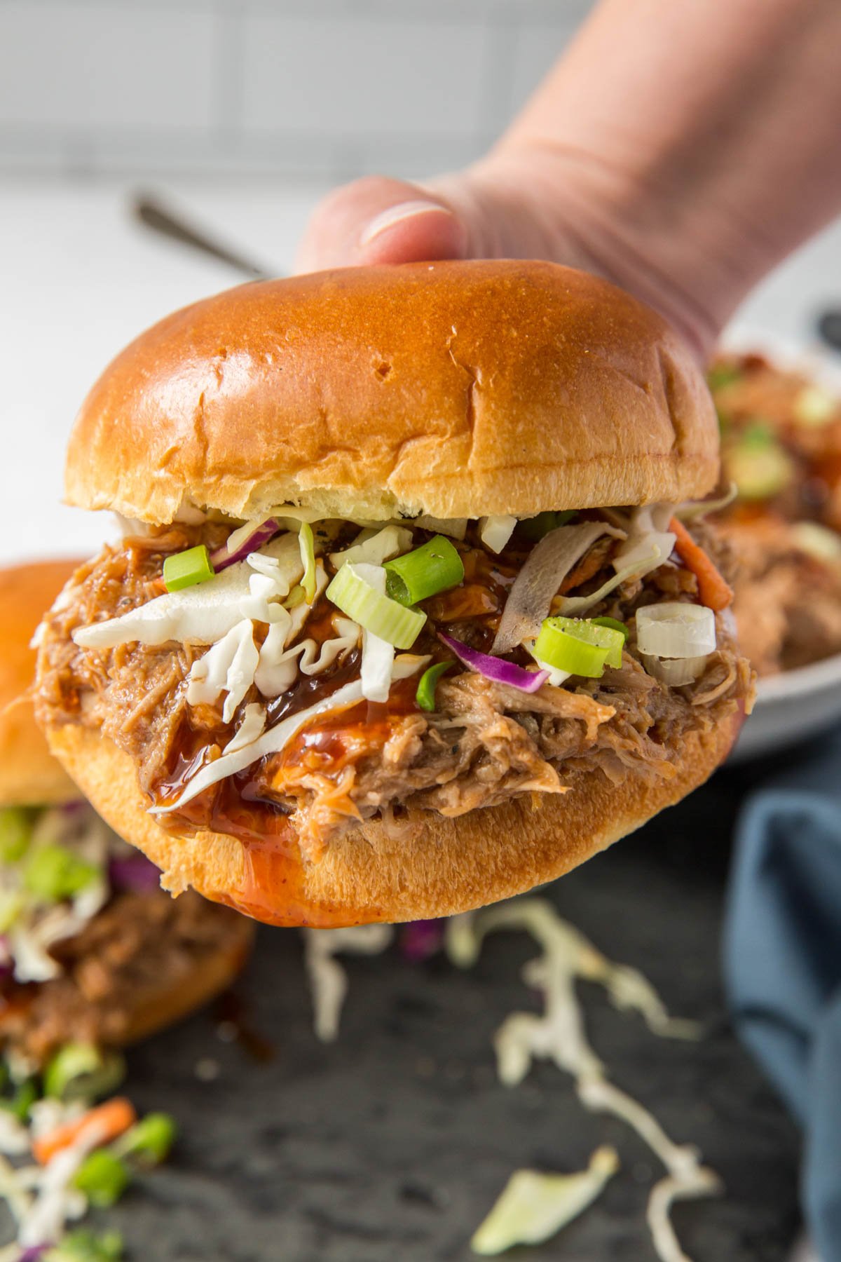 a hand hold a bbq pulled pork sandwich