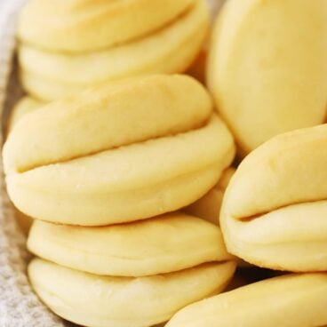 parker house rolls in a basket with a gray and white towel underneath