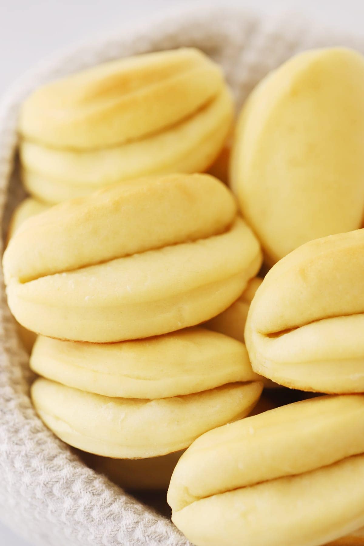 parker house rolls in a basket with a gray and white towel underneath