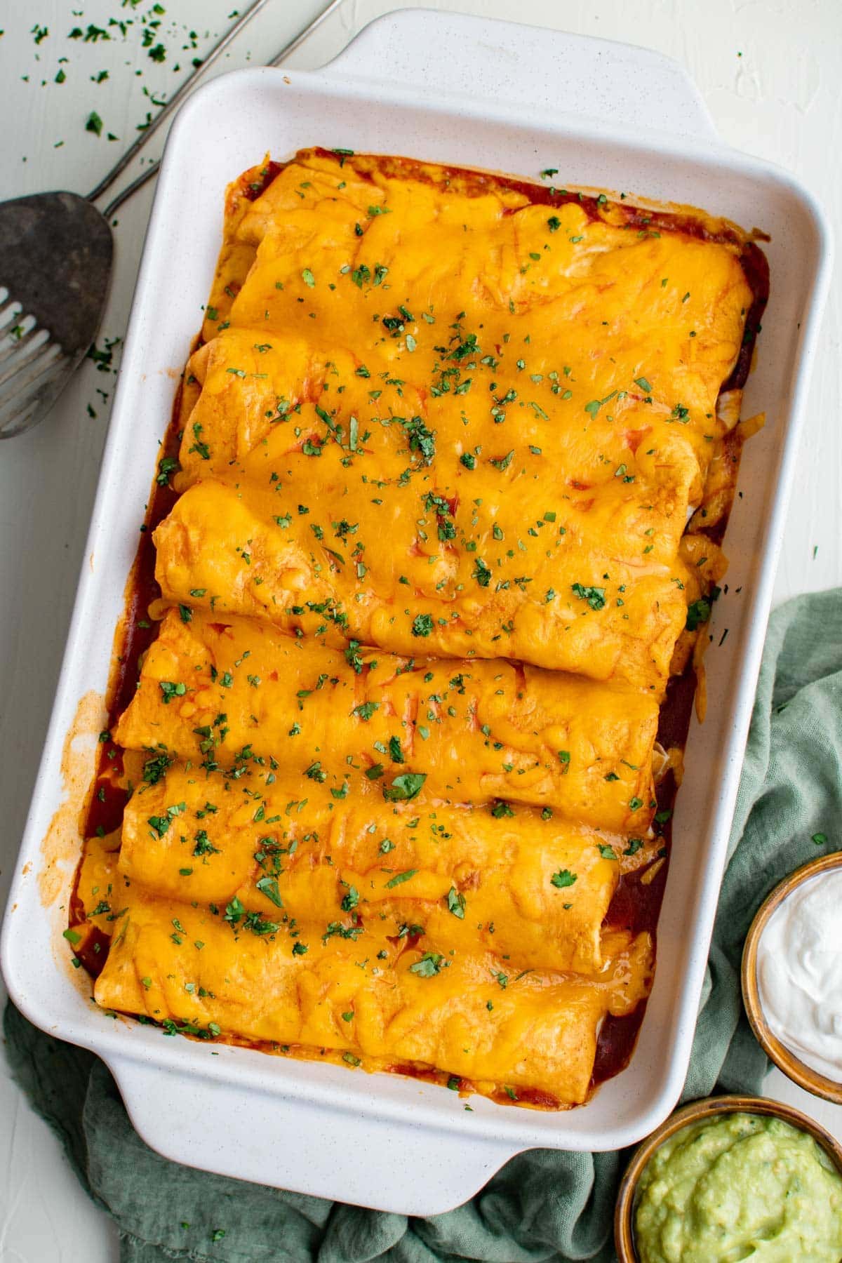 smothered wet burritos arranged in a large baking dish