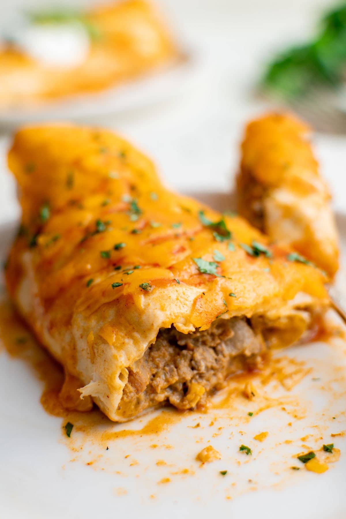 wet burrito with creamy beef and bean filling on a white plate
