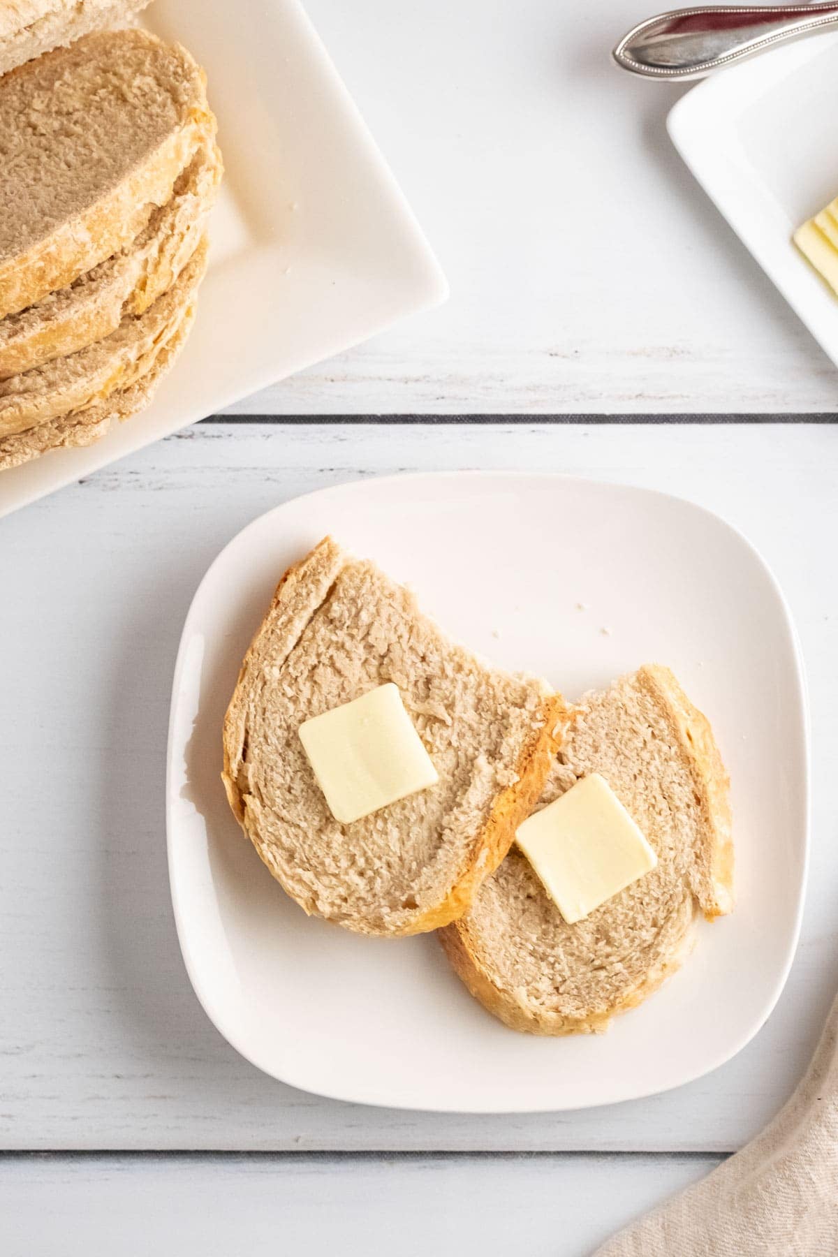 sliced sourdough bread with butter, white plates