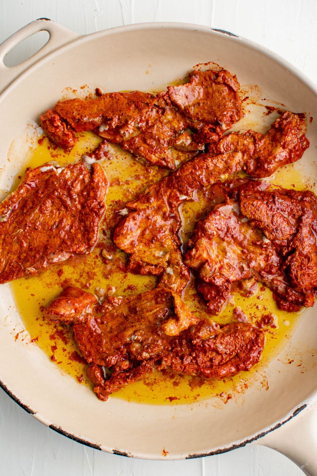 marineted slices of pork cooking in a skillet