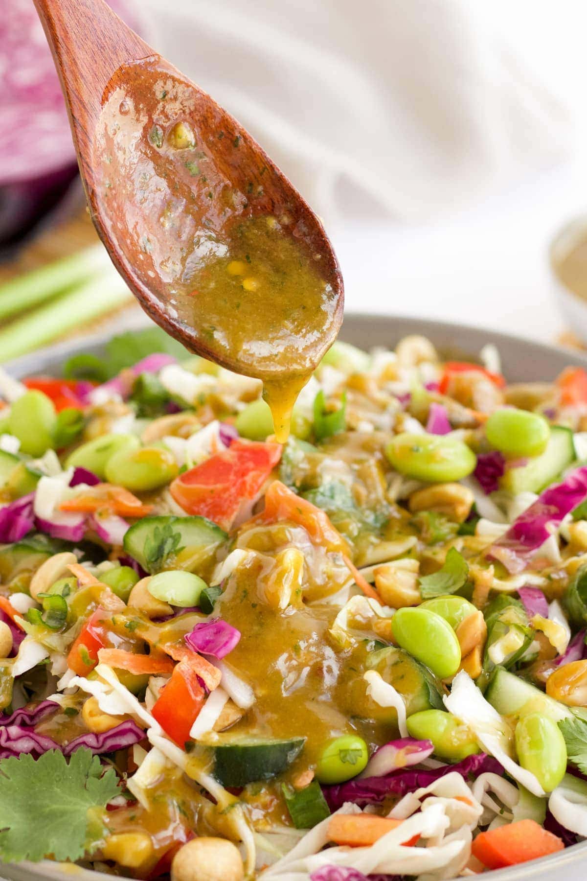 Thai Peanut Dressing being drizzles over a Thai Salad 