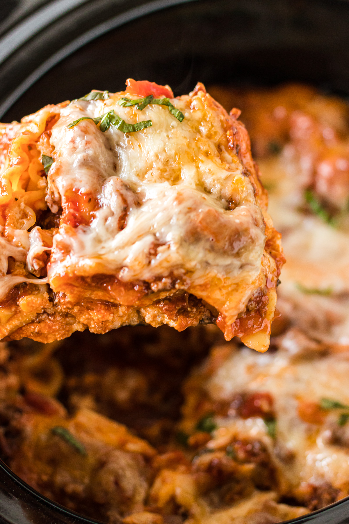 portion of lasagna being lifted from the slow cooker