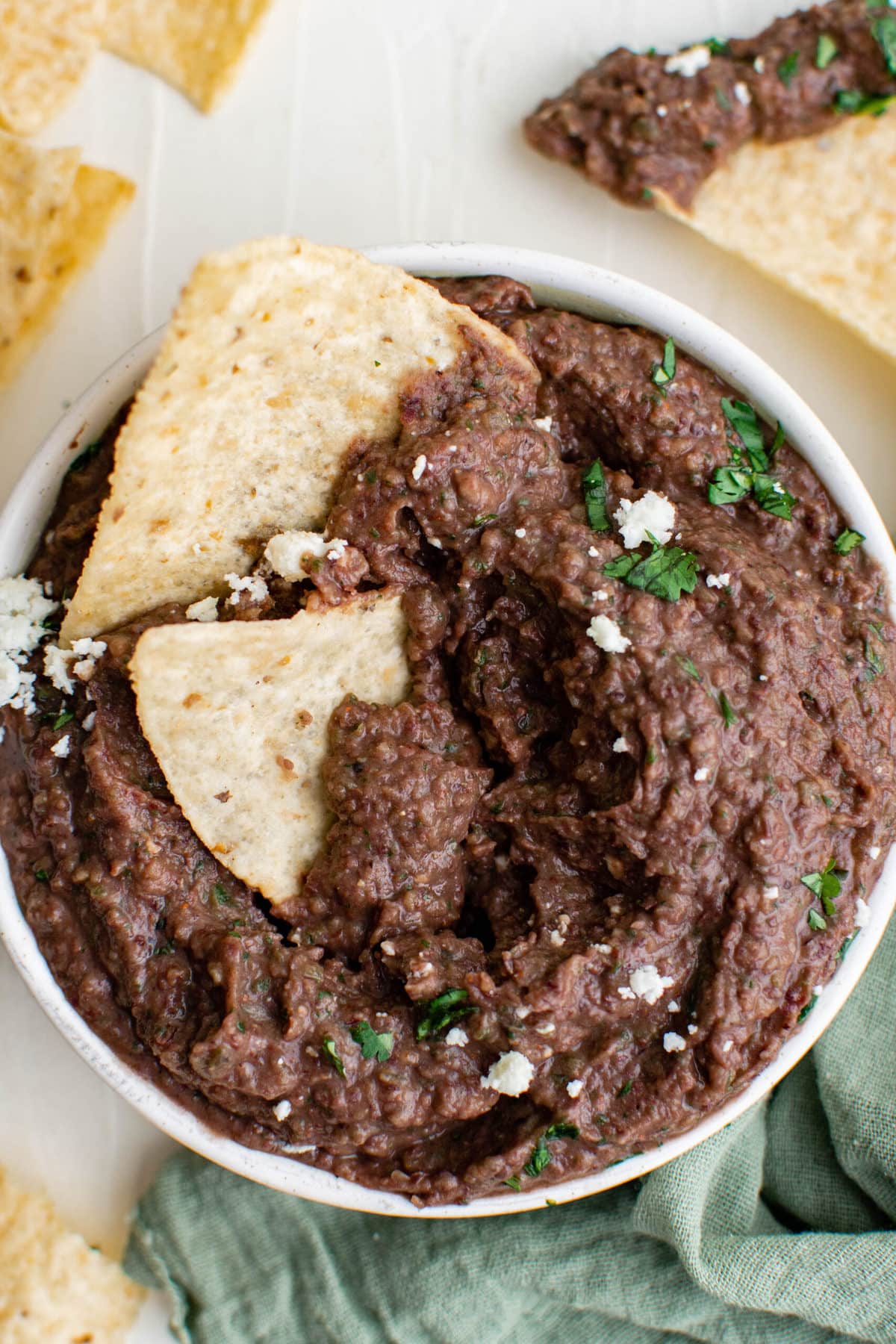 black bean dip in a white bowl, cotija cheese, cilantro, tortilla chips