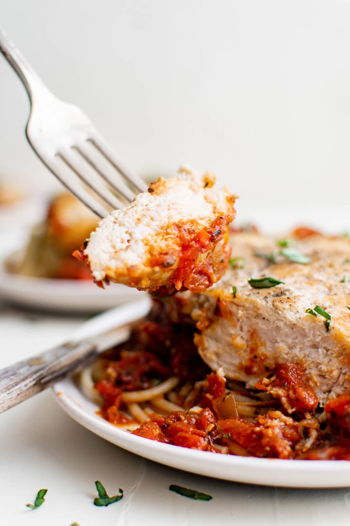 chicken breast, fork, pomodoro sauce, spaghetti, white plates