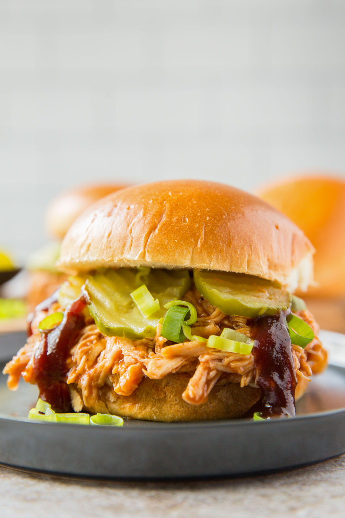 shredded instant pot shredded barbecue chicken sandwich a black plate with pickles