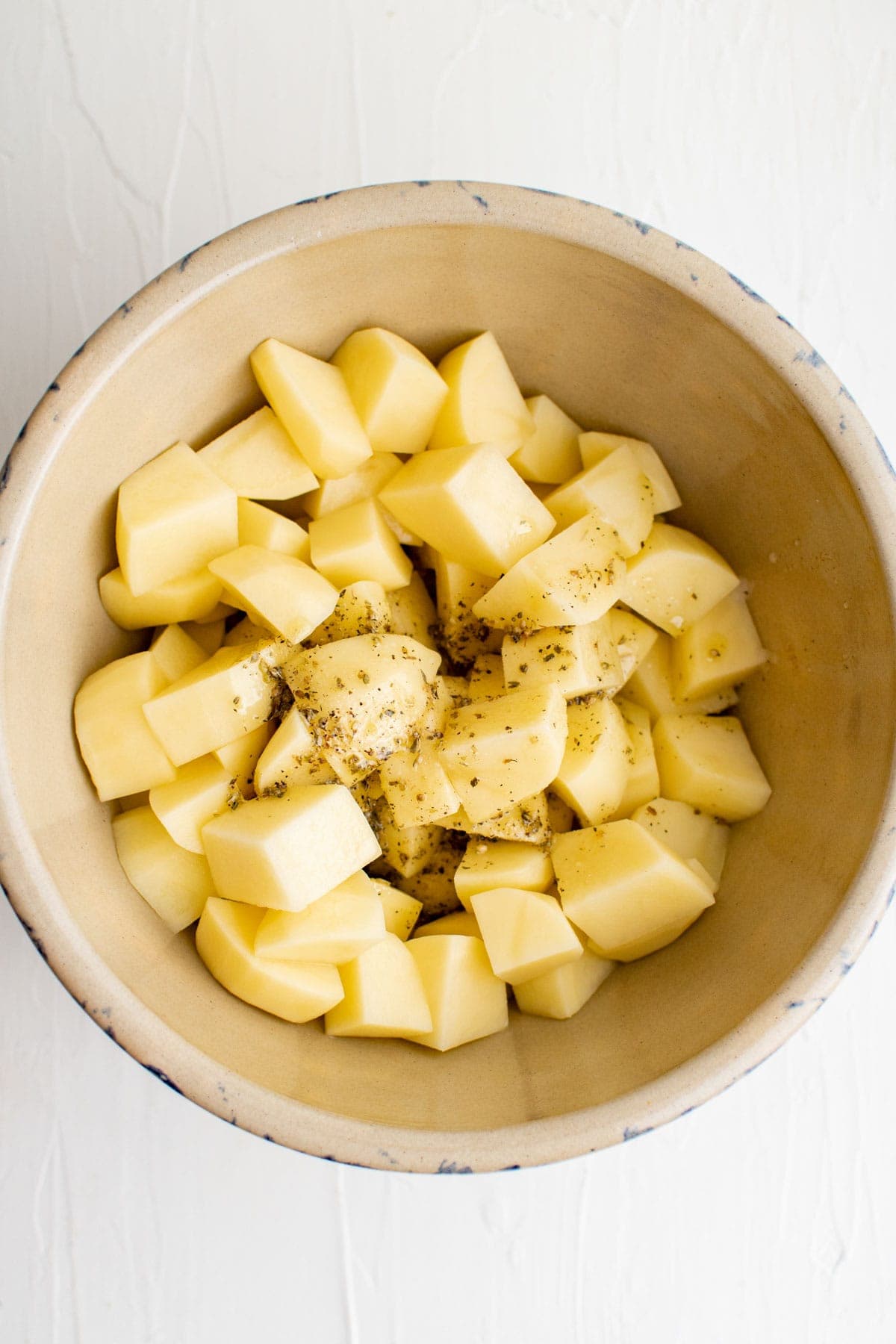 potatoes in a bowl with olive oil and seasoning