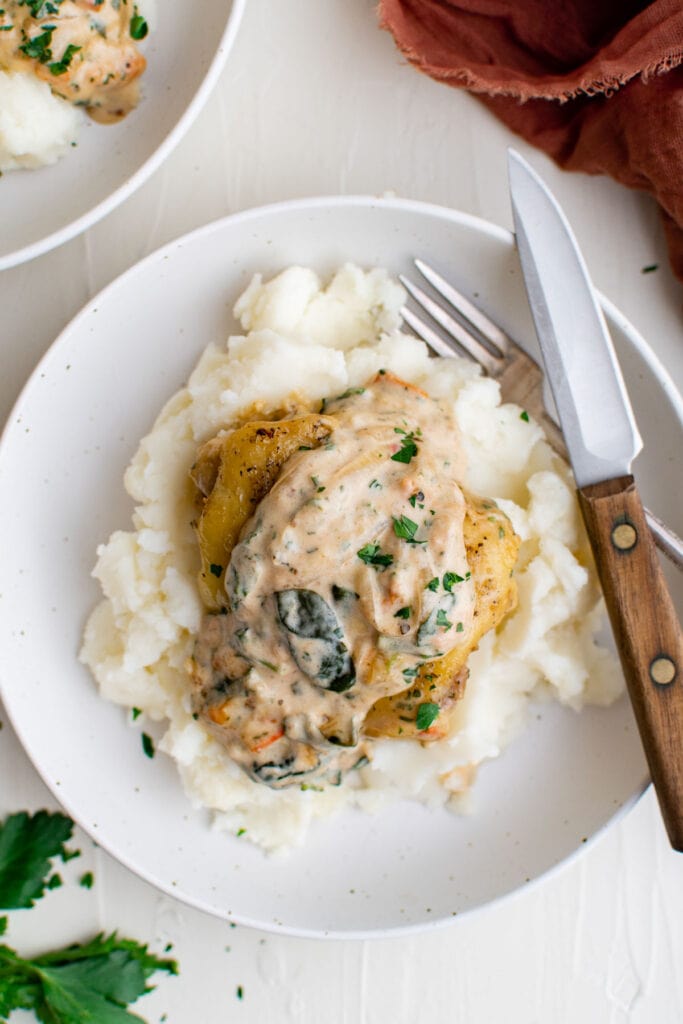 Chicken thigh served with mashed potatoes on a white plate