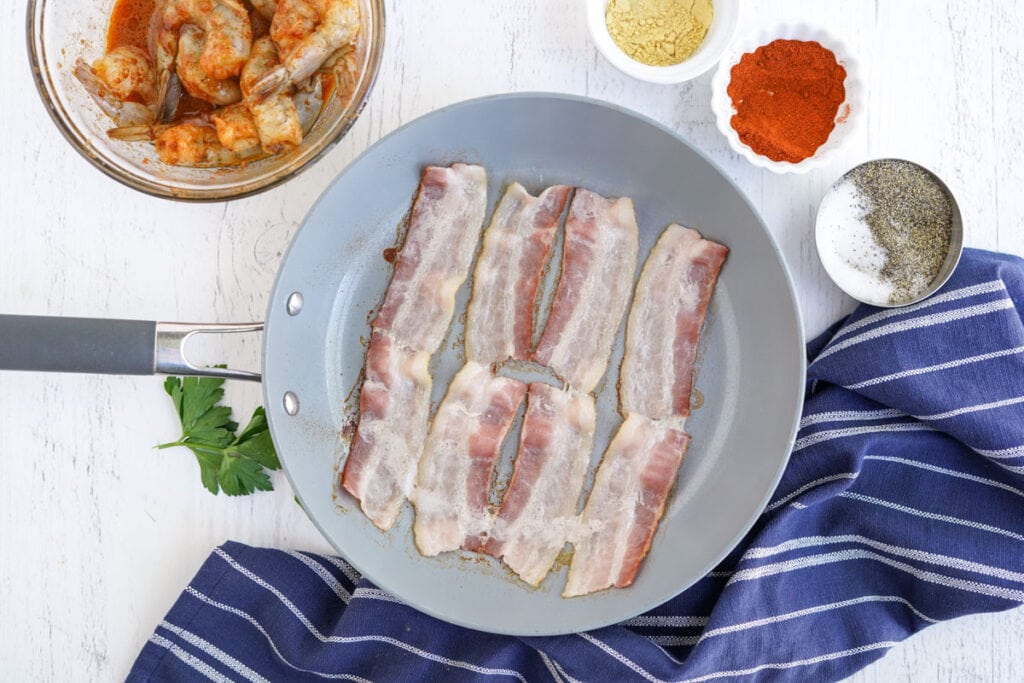 pieces of bacon frying in a skillet
