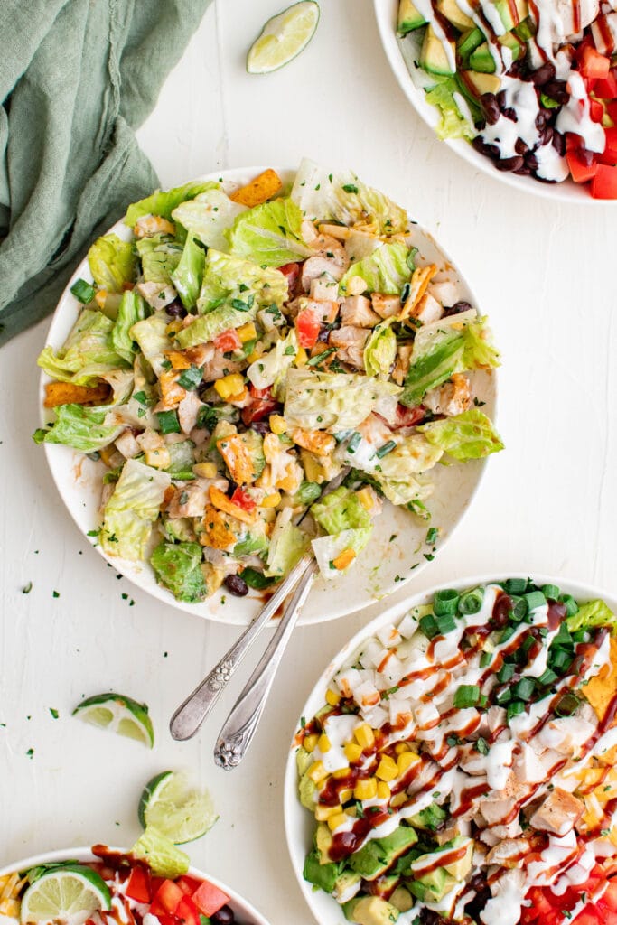 mixed bbq chicken salae on white plates with forks and a green napkin