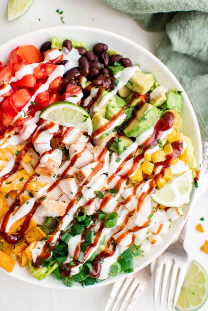 salad on a white plate with chipcken, onions, beans, tomatoe, corn, cheese