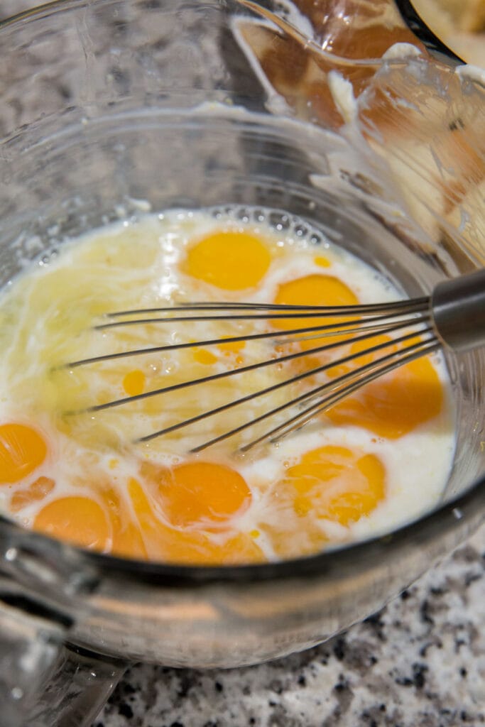 eggs and milk in a glass bowl with a whisk