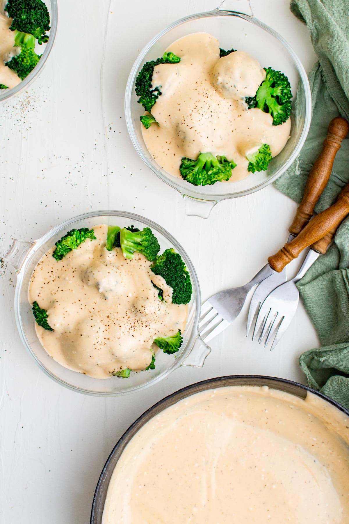 ckillet with cheese sauce, broccoli with cheese on plates, forks, 