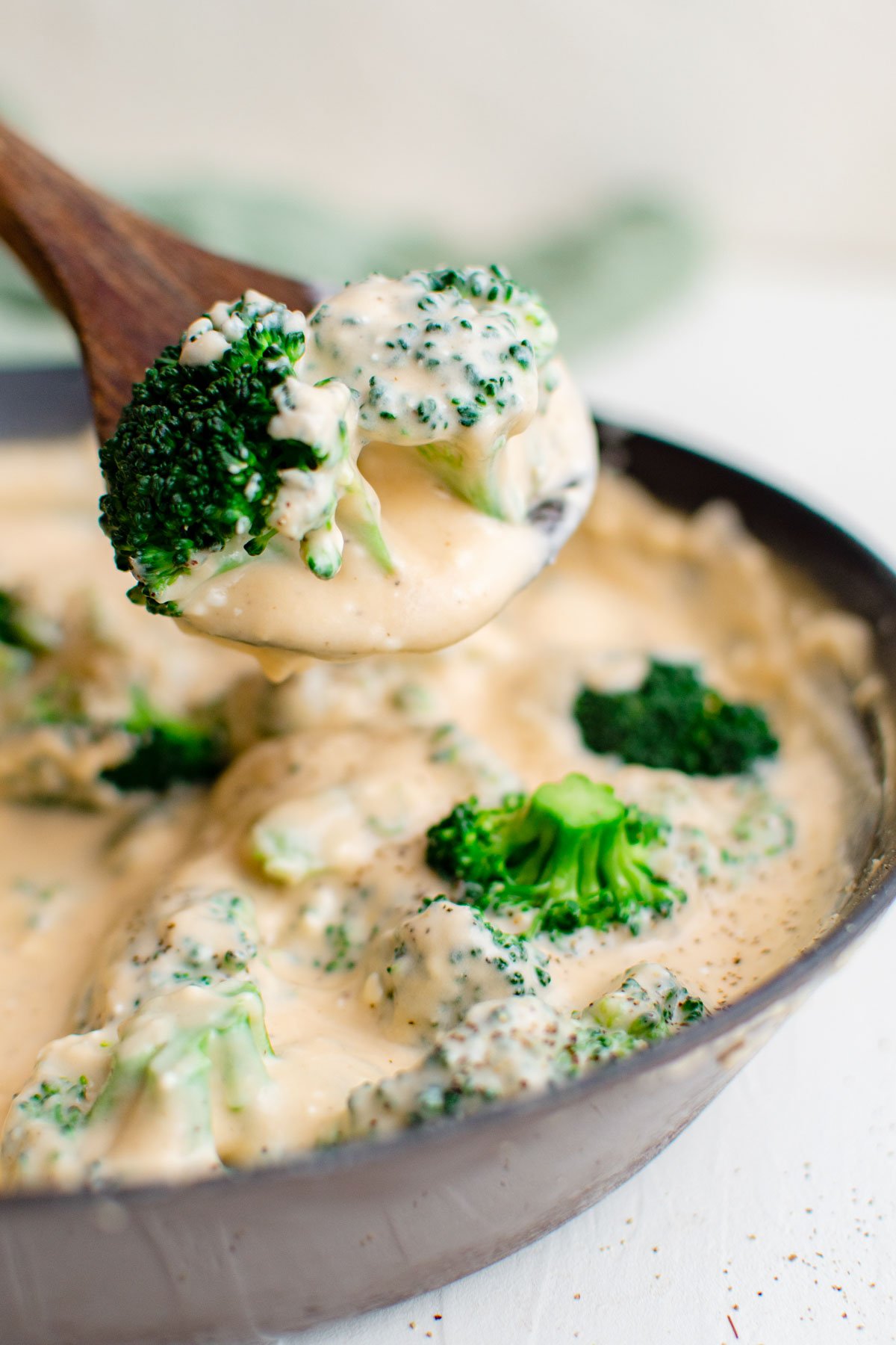 skillet with cheese sauce, broccoli, wood spoon