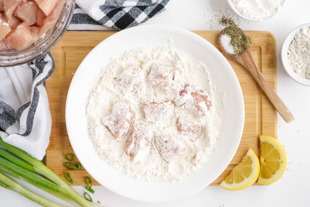 chicken pieces in flour mixture in a white bowl