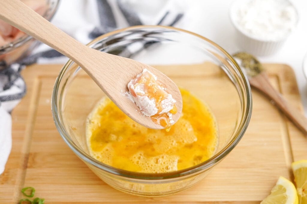 egg batter for crispy fried chicken in a bowl, wooden spoon 