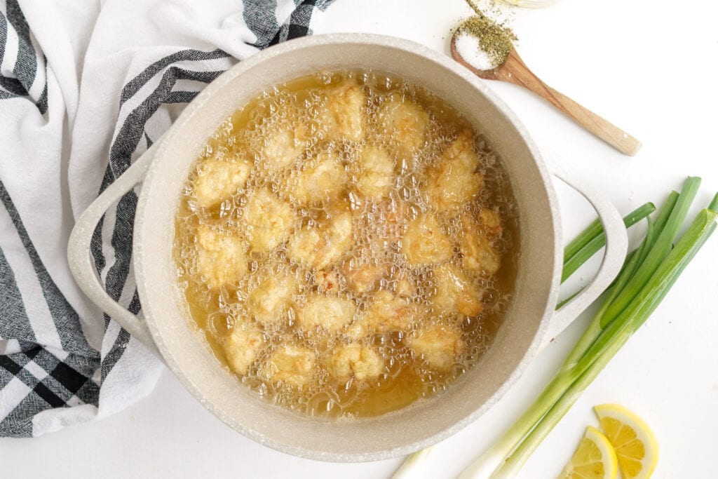 deep pan with bubbling oil, battered chicken frying