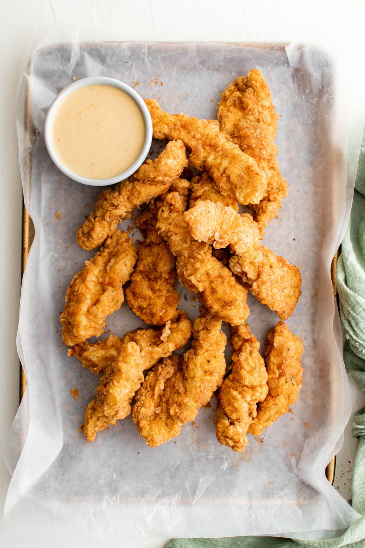 frie chicken tenders on paper lined tray, white dish with honey mustard dip