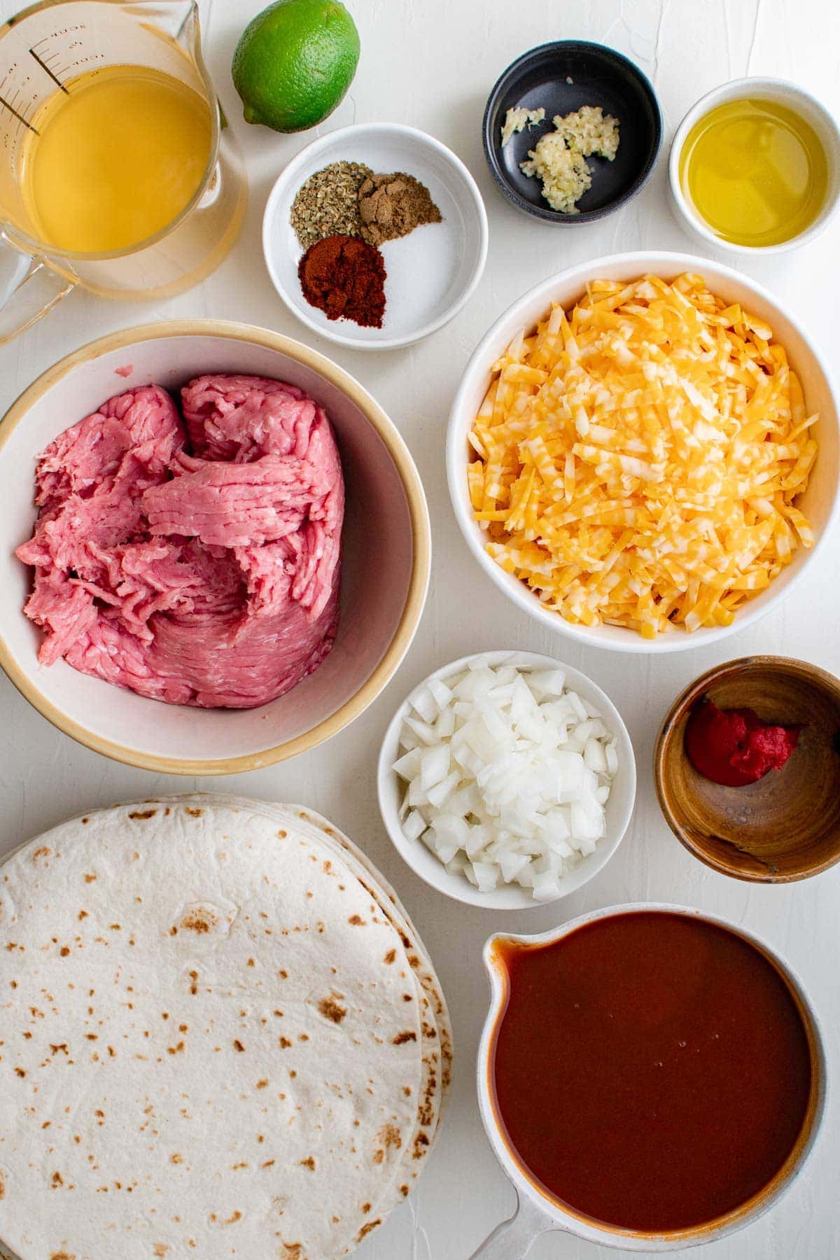 ingredients for ground turkey enchiladas in small bowls, tortillas