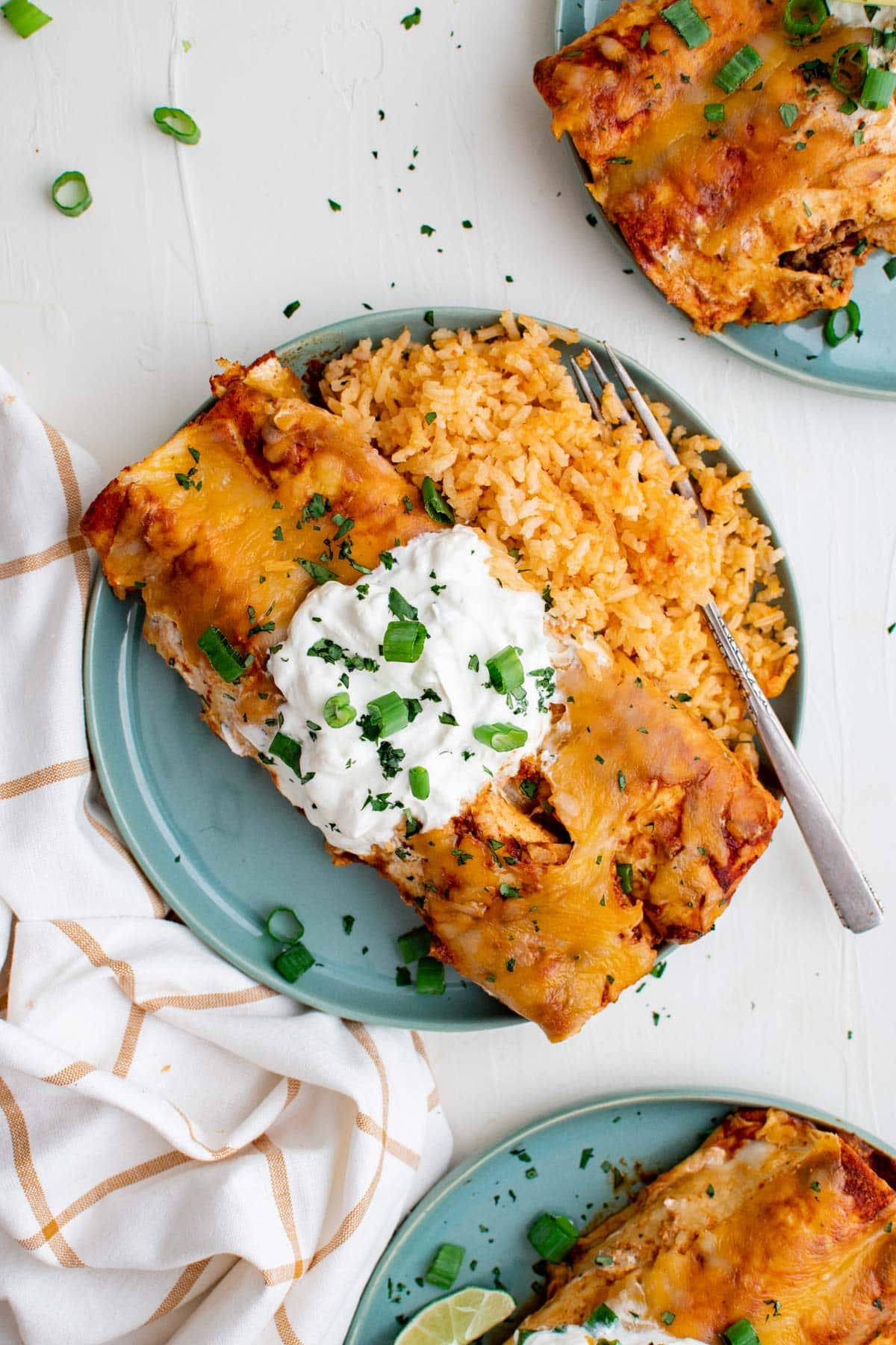 enchiladas on a blue plate with rice and a fork