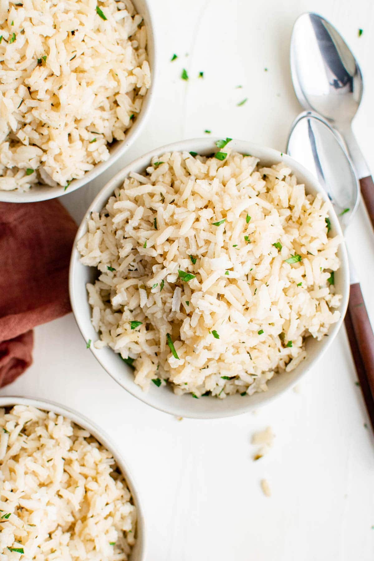 close up of three bowls with rice, spoons, pink napkin