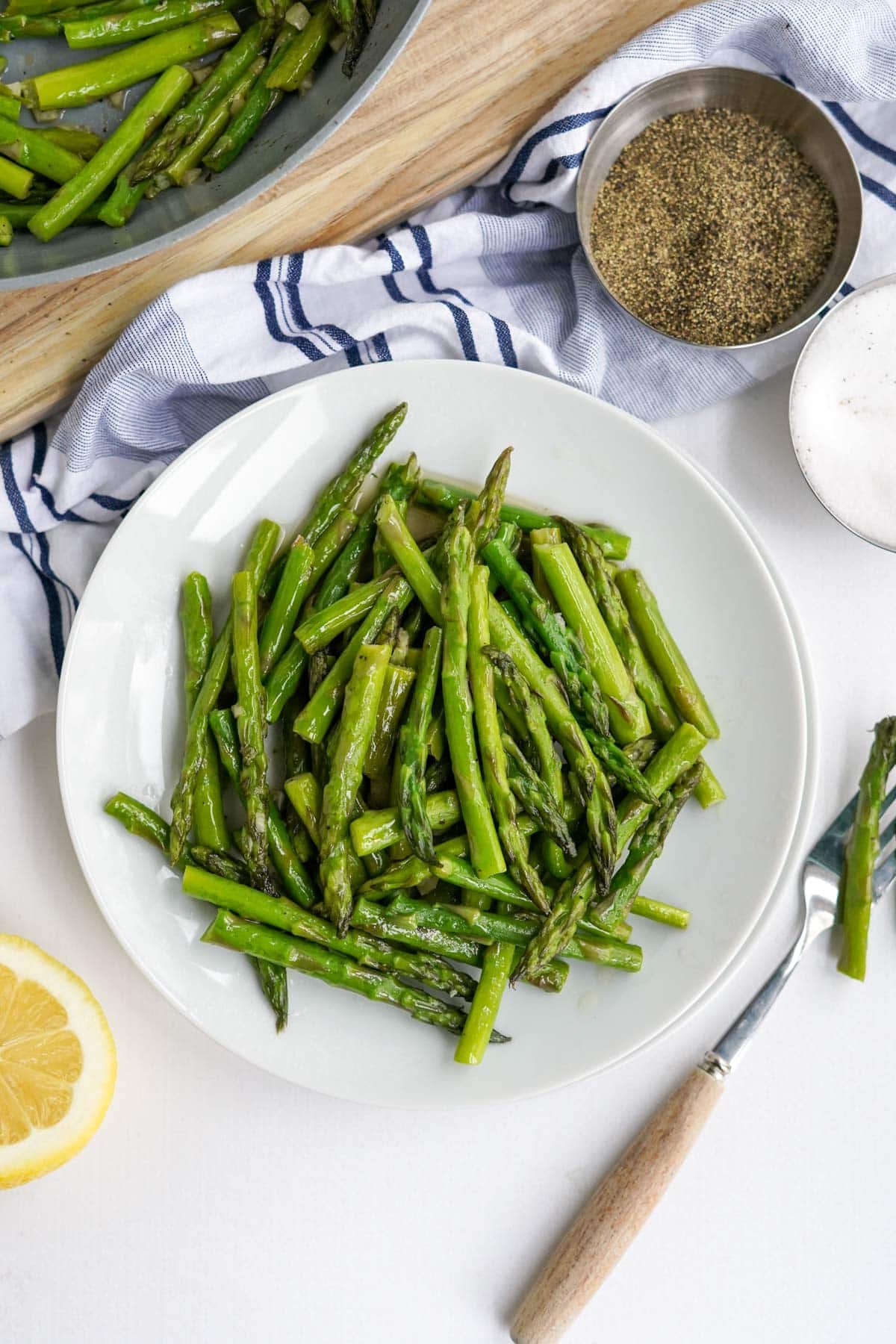 small white plate with asparagus, blue and white napkin, lemon