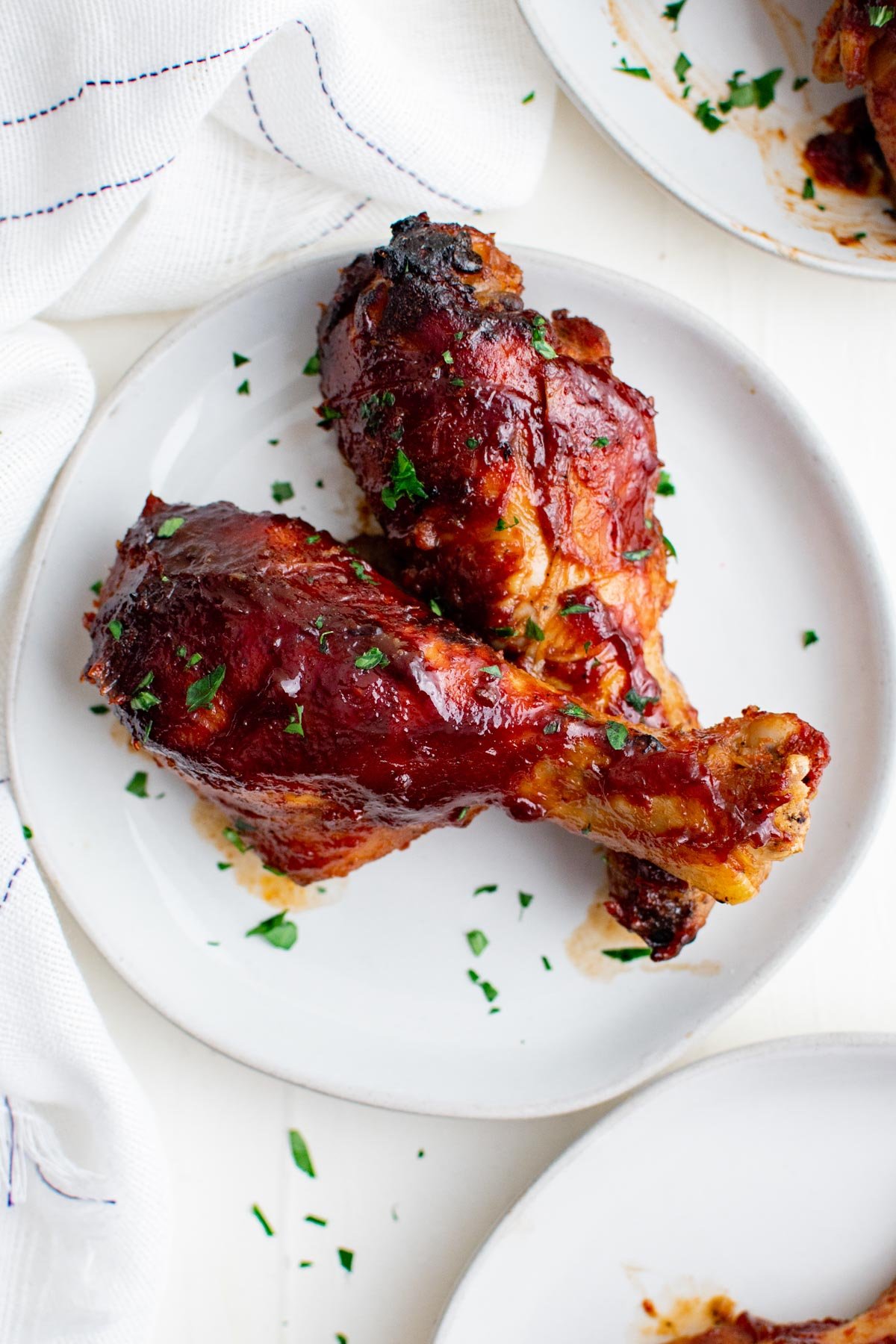 chicken legs with bbq sauce on a white plate