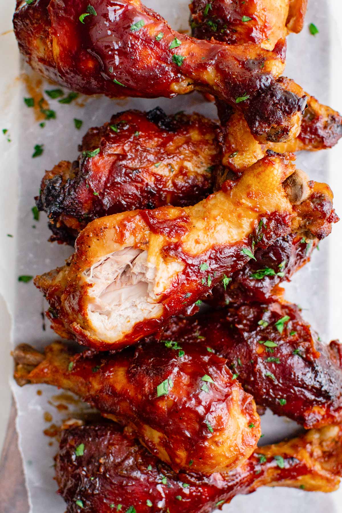 bbq chicken drumsticks on a white platter with minced parsley